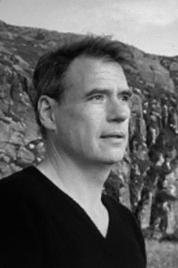 Black and white photo of a person outdoors with mountains in the background