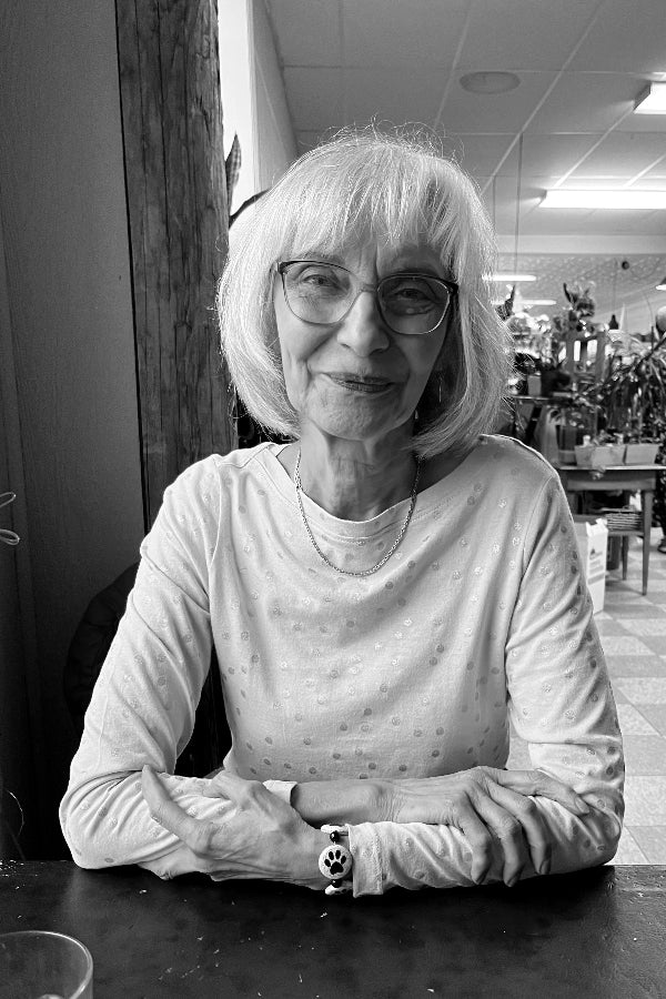 Black and white photo of a woman sitting at a table in an indoor setting