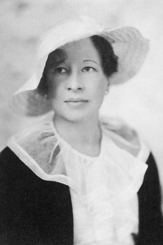 Black and white portrait of a woman wearing a hat and coat with a light background