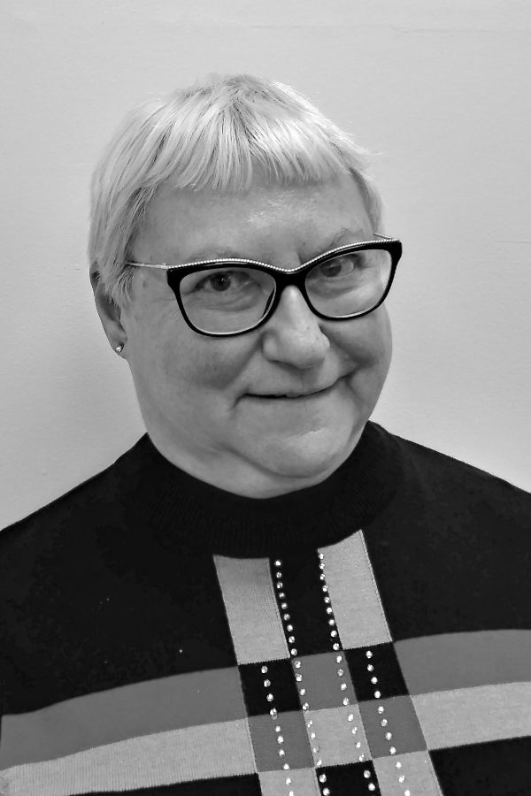 Black and white portrait of a person wearing glasses and a patterned sweater.