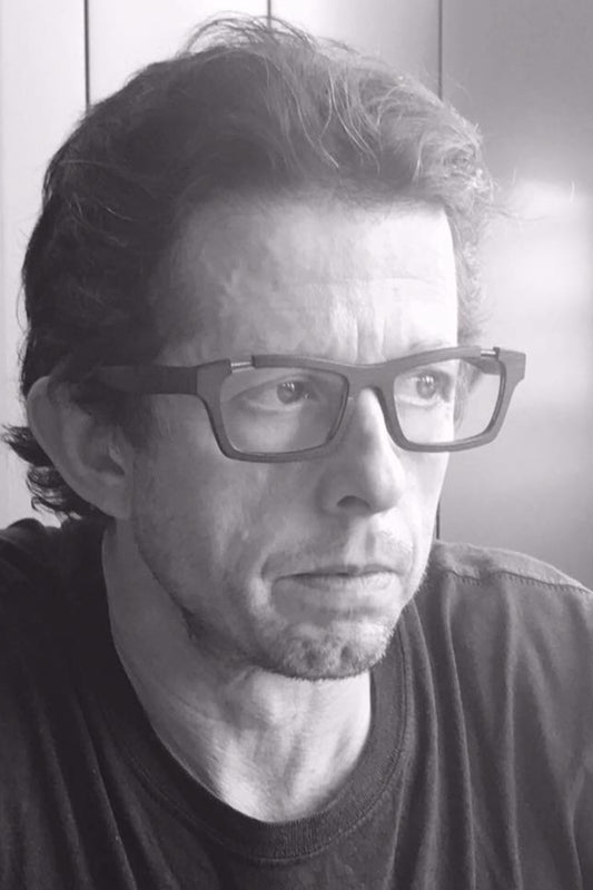 Black and white portrait of a Alex Elford wearing glasses.