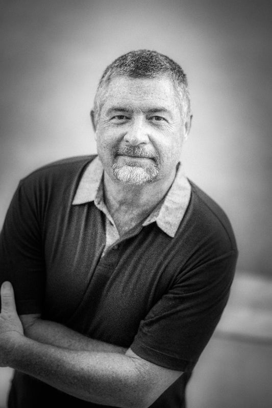 Black and white portrait of a man with arms crossed against a blurred background