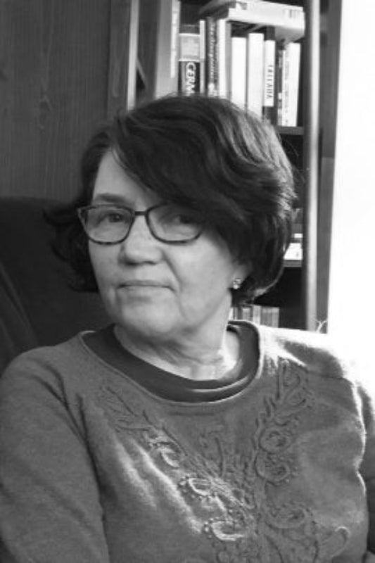 Black and white photo of a person sitting in front of a bookshelf