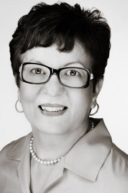 Black and white portrait of a woman wearing glasses and a pearl necklace.