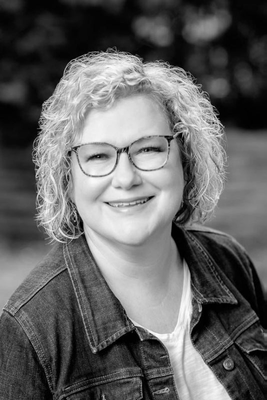 Black and white photo of a person with glasses and curly hair