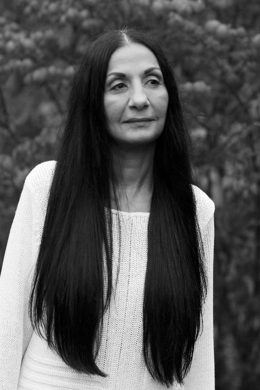 Black and white portrait of a woman with long hair against a blurred natural background