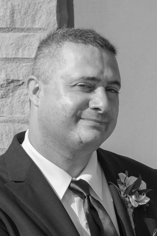 Man in a suit with a boutonniere against a stone wall background