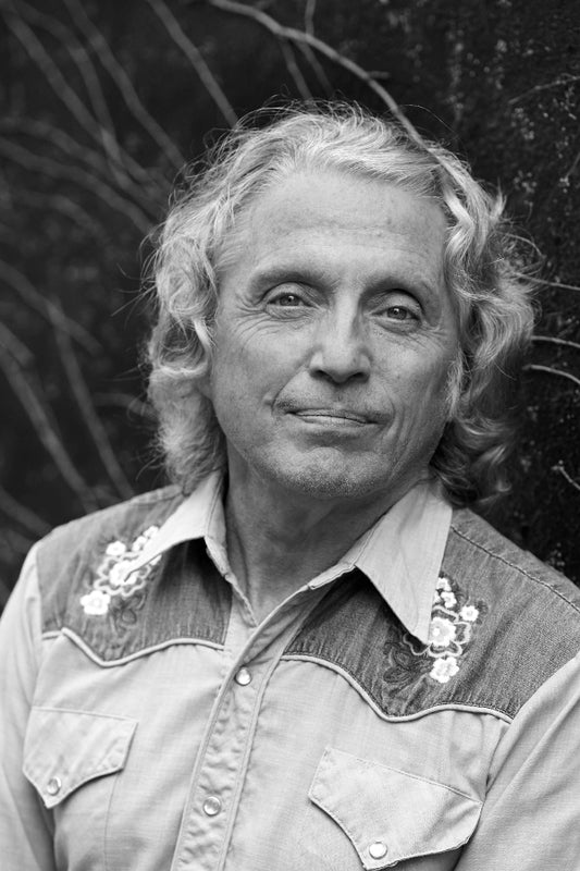 Black and white portrait of a person wearing a patterned shirt with floral embellishments.