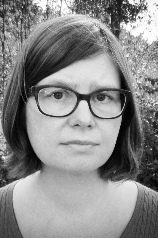 Black and white photo of a person with glasses and shoulder-length hair.