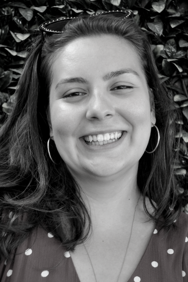 Black and white photo of a woman with a smile against a leafy background