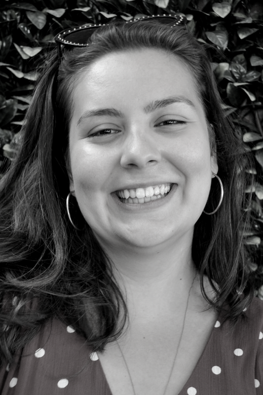 Black and white photo of a woman with a smile against a leafy background