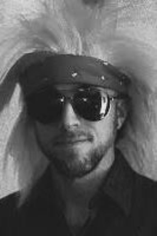 Person wearing a large feathered headdress and sunglasses in a black and white photo