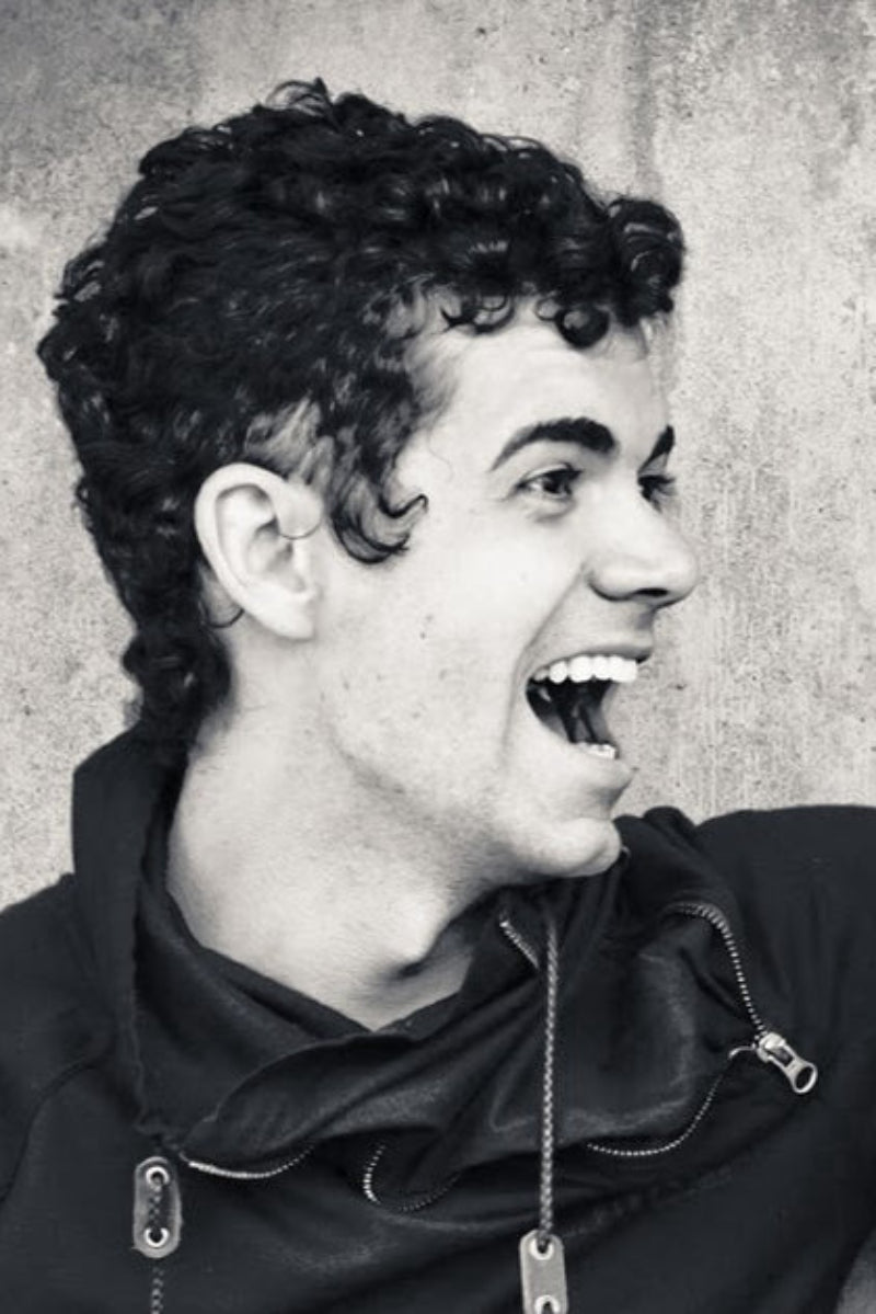 Black and white photo of Mark LeRoy laughing against a textured wall.