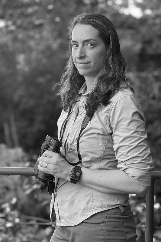 Black and white photo of a person holding binoculars with a natural background