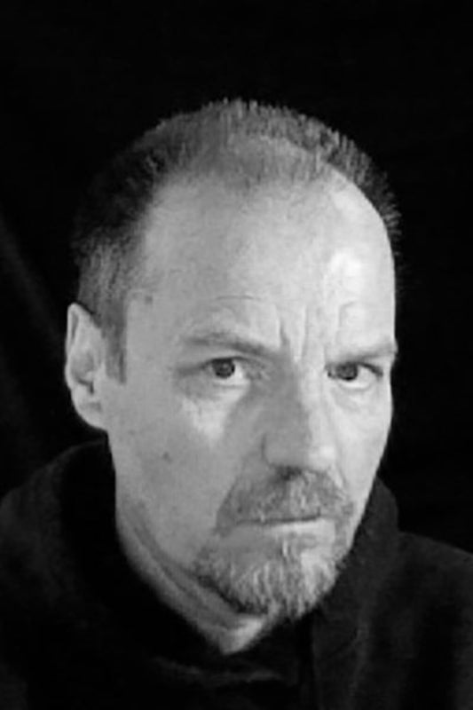 Black and white portrait of a man with a neutral expression against a dark background