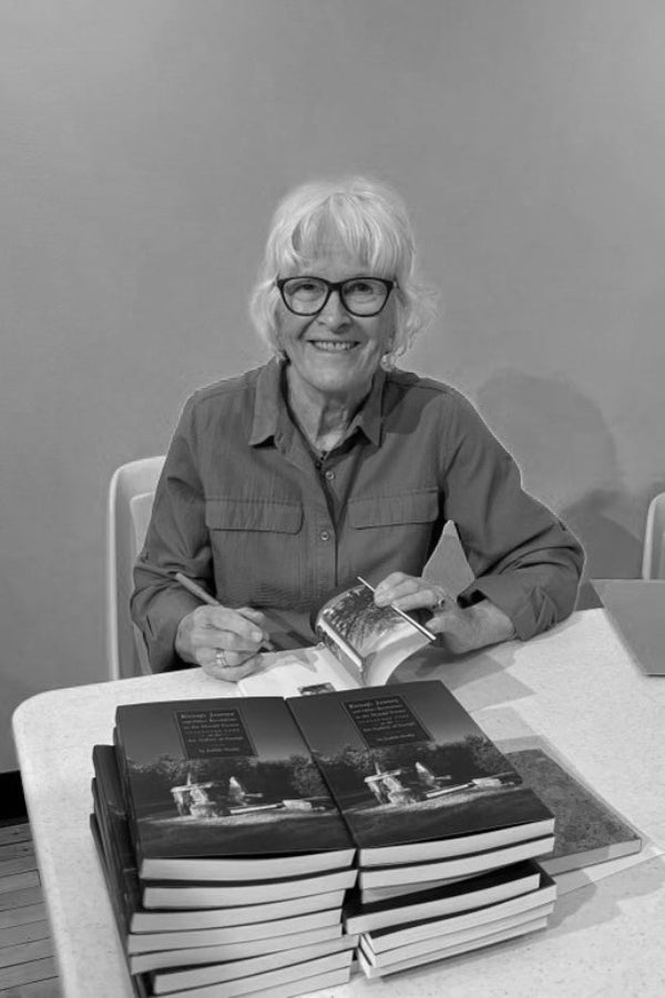 Person sitting at a table with books, smiling in a black and white photo