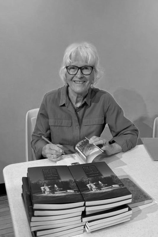 Person sitting at a table with books, smiling in a black and white photo