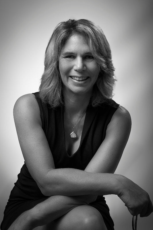 Black and white portrait of a woman with arms crossed on a plain background