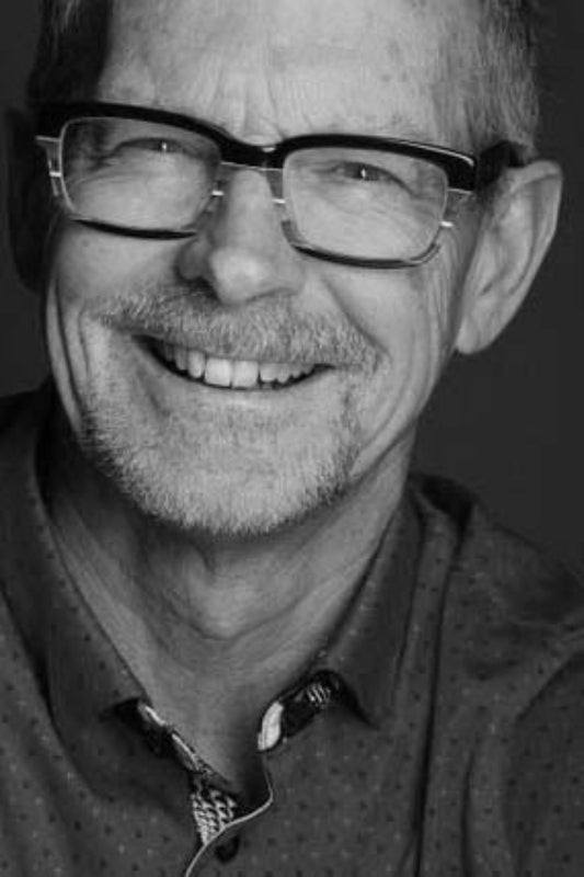 Black and white portrait of a man wearing glasses with a dark background