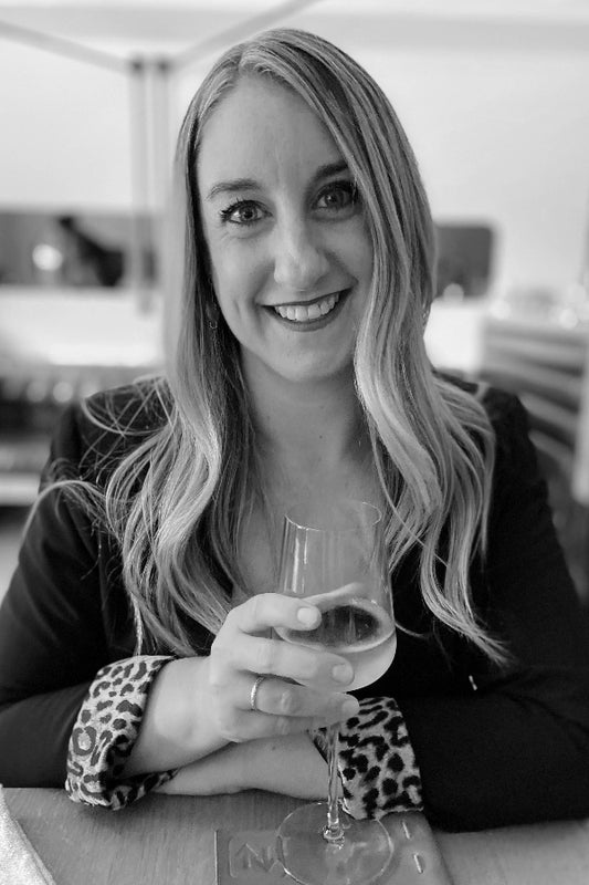 Black and white photo of a woman holding a glass of wine indoors.
