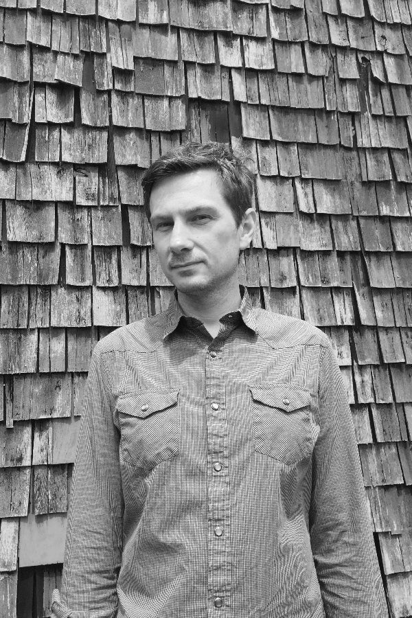 Man standing in front of a wooden shingle wall