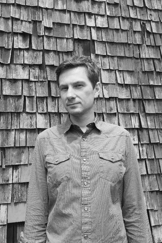 Man standing in front of a wooden shingle wall