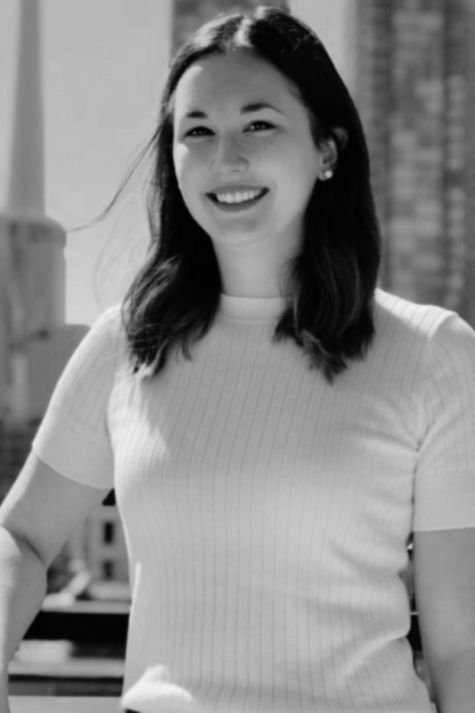 Black and white photo of a woman smiling outdoors