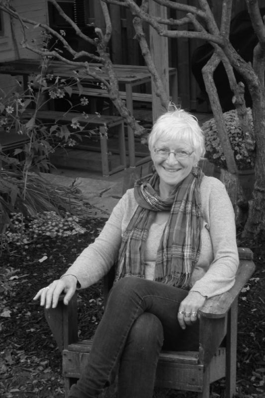 Black and white photo of a woman sitting outdoors on a chair.