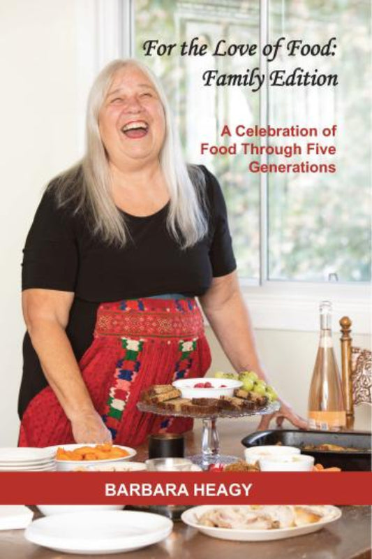 Book cover featuring a woman in an apron with a cake, titled 'For the Love of Food: Family Edition' by Barbara Heagy.