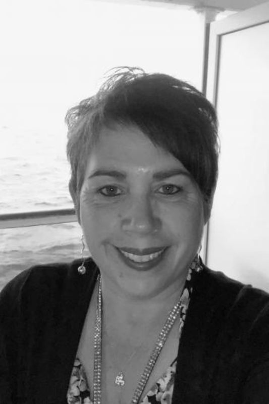 Black and white photo of a person with short hair and a necklace.