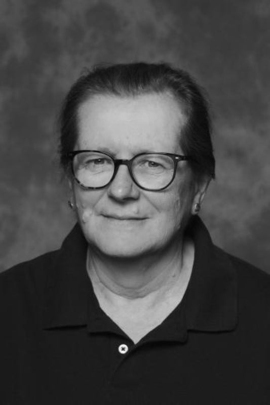Black and white portrait of a person wearing glasses and a dark shirt against a textured gray background